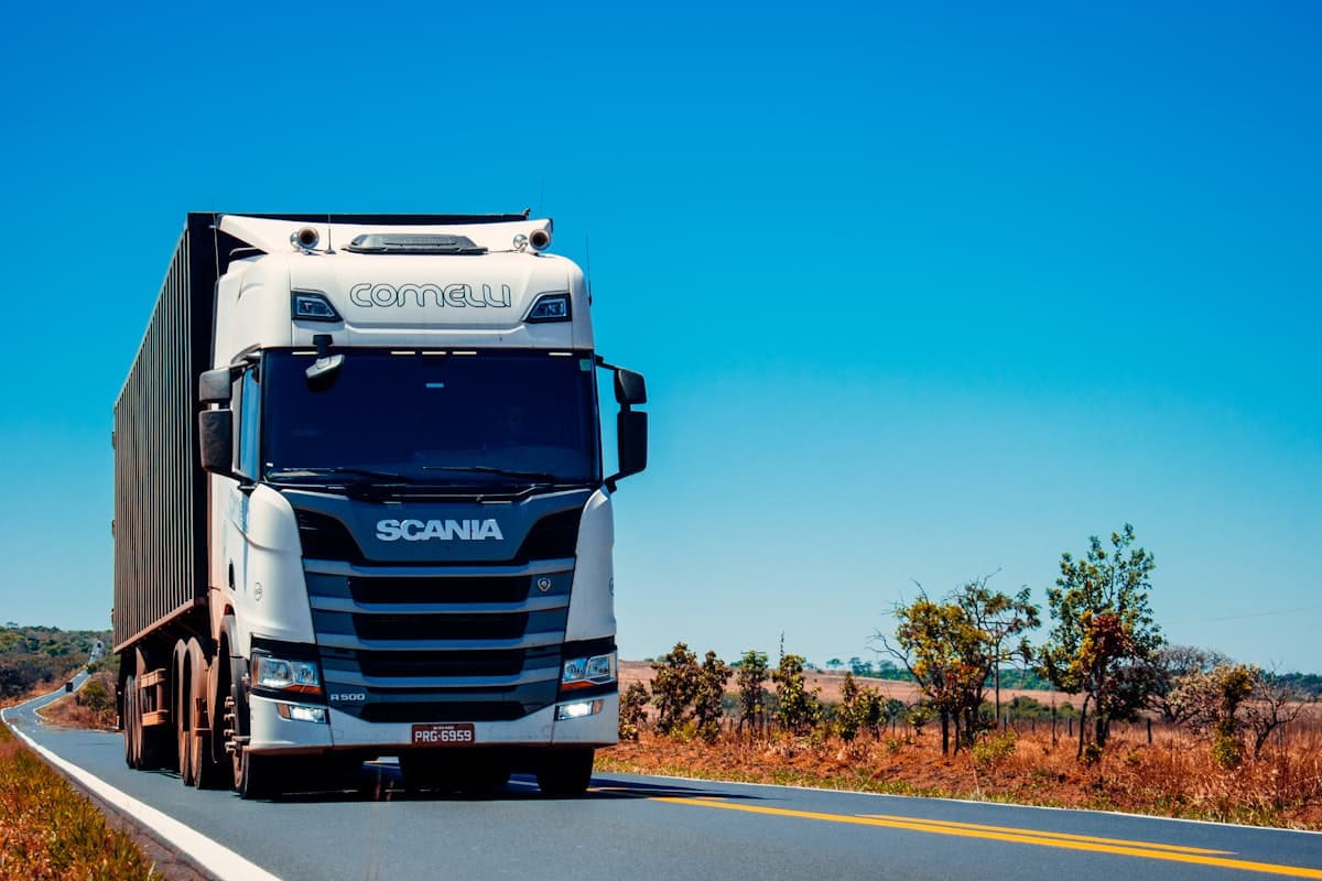 White semi truck driving on an open road under a blue sky